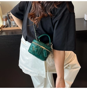 Detail of forest green mini quilted chain bag with gold metal zipper and handle