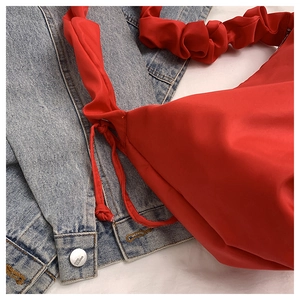 Detail of red satin crossbody bag with scrunchie strap and drawstring side accents