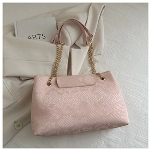 Détail du sac rose texture serpent avec chaîne dorée sur un fond stylé et épuré
