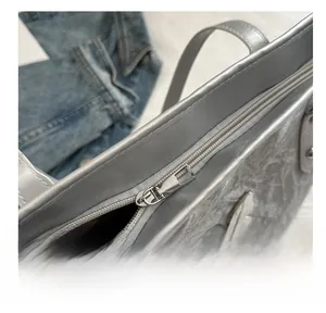 Detail shot of smooth silver zipper and butterfly charm on metallic tote bag