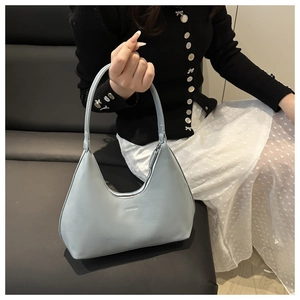 Detail of light blue hobo bag with FASHION text and matte faux leather texture