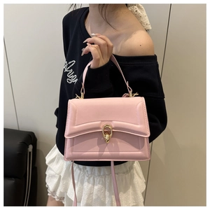 Detailed view of a pink structured crossbody bag with a golden circular metal lock