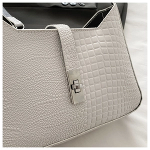 Close-up of white crocodile and lizard pattern crossbody bag with silver metal lock