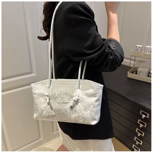 Detail shot of white shoulder bag featuring delicate floral butterfly lace embroidery