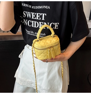 Nahaufnahme der gelben gesteppten Mini-Box-Tasche mit Goldkette und Doppelreißverschluss