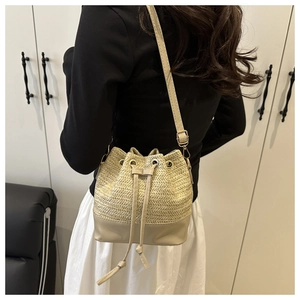 Detail of woven straw bucket bag with leather base and drawstring on female model