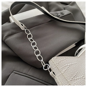 Detailed macro view of the white crocodile texture and silver chain strap on the handbag