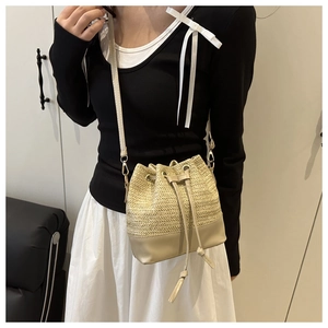 Detail of straw woven bucket bag featuring adjustable strap and drawstring closure