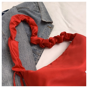 Top view of red pleated shoulder bag with soft cloud-like texture on denim jacket