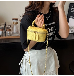 Detail of yellow quilted mini bag with gold double zippers and elegant chain strap