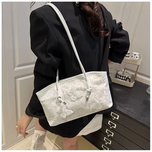 Detail of white lace tote bag with 3D butterfly embroidery and leather trim handles