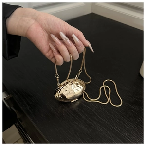 Gros plan détaillé d'un mini sac doré en forme de coquillage avec texture métal martelé