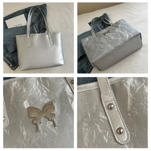 Close-up of metallic silver tote bag showing crinkled texture and butterfly logo