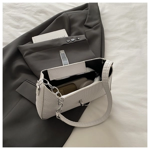 Detailed interior of a white croc-embossed handbag with zipper pocket and silver chain