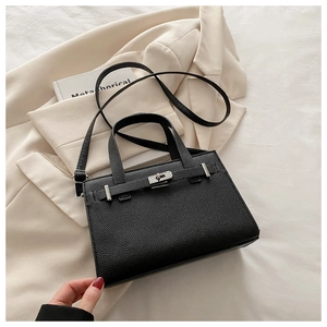 Macro shot of black lychee grain leather texture and silver buckle on a stylish handbag