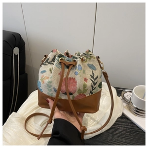 Close-up of ethnic bucket bag with floral brocade fabric and brown leather details