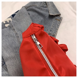 Detail view of red pleated nylon bag with silver metal zipper on denim background