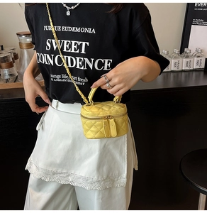 Close-up of bright yellow quilted mini bag with golden chain and leather handle