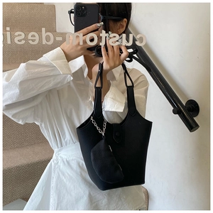 Detail of black lychee grain leather bucket bag with a matching mini zip pouch attachment