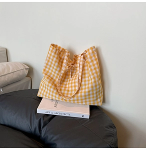 Detail of yellow gingham cotton canvas tote bag on a black leather seat with books