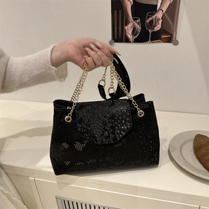 Sac à main chic noir à texture serpent avec chaînes dorées dans un décor de style de vie
