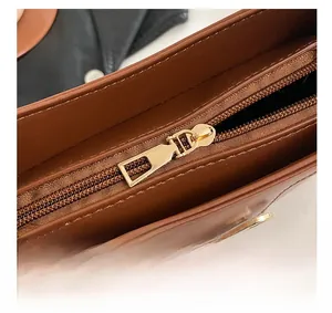Detail view of gold-tone metal zipper and crocodile pattern on dark brown handbag