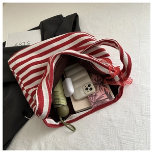 Detail of red striped canvas tote bag showing spacious interior with books and umbrella