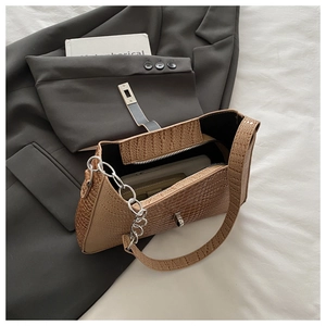 Detail view of brown crocodile texture shoulder bag with silver metal chain on blazer