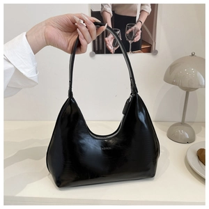 Detail of black glossy hobo bag with FASHION embossed lettering and sleek top handle
