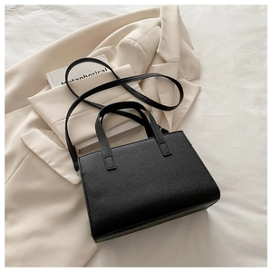 Close-up of black lychee texture tote bag on beige blazer for a minimalist office style
