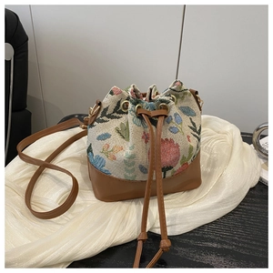 Detail of vintage floral drawstring bucket bag with leather base and metal hardware