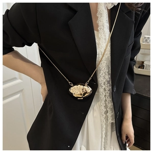 Detailed view of the gold oval mini bag pendant with hammered texture and fine metal chain