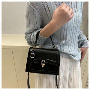 Classic black flap crossbody bag with oval gold lock shown styled on a model outfit