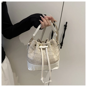 Detail of woven straw bucket bag showing white leather trim and drawstring closure