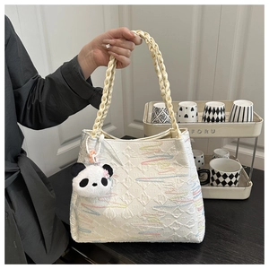 Detail of cream tote bag with textured embossing, wave embroidery and panda charm