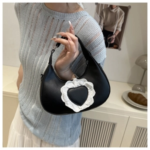 Dettaglio della borsa a mezzaluna in pelle nera con pizzo bianco e toppa a forma di cuore