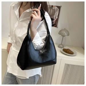 Detail of black glossy leather underarm bag with embossed FASHION lettering