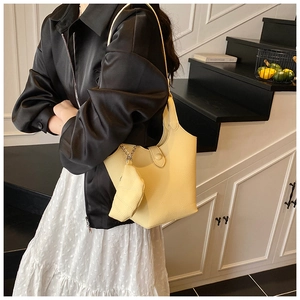 Detail of light yellow lychee grain leather bucket bag with hanging small zipper pouch