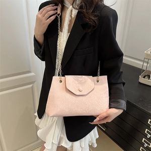 Sac sous le bras rose à motif serpent avec chaîne dorée porté par un mannequin