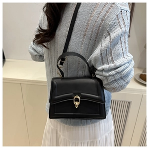 Detail of black crossbody bag with padded texture and gold oval metal buckle
