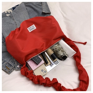 Detail of red ruched shoulder bag showing large capacity with phone and umbrella inside