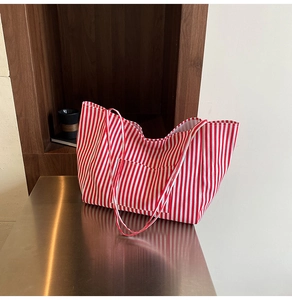Detail of red and white striped canvas tote bag with front pocket on a reflective desk