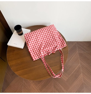 Detail view of red and white plaid cotton tote bag with bow knot on wood table