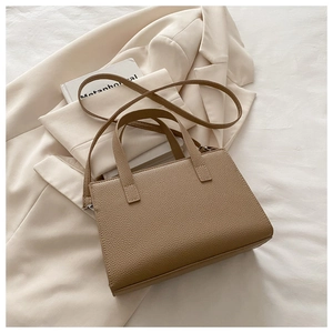 Close-up of tan lychee-textured faux leather bag with handle and detachable strap