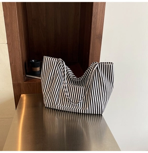 Detail of a large black and white striped canvas tote bag with front pocket and dual straps