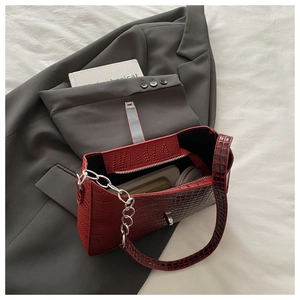 Macro detail of dark red faux crocodile leather shoulder bag with silver chain and metal buckle
