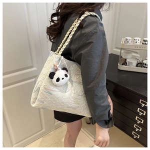 Detail of white textured bucket bag with embroidery, woven strap and panda charm accessory