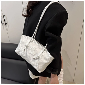 Detail of white lace underarm bag with 3D butterfly embroidery worn by a model