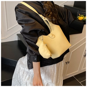 Close-up of pale yellow lychee leather bucket bag with a mini shell-shaped charm