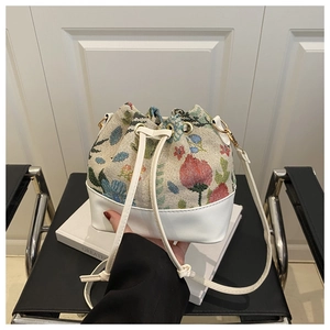 Macro shot of floral tapestry fabric and white leather base on drawstring bucket bag